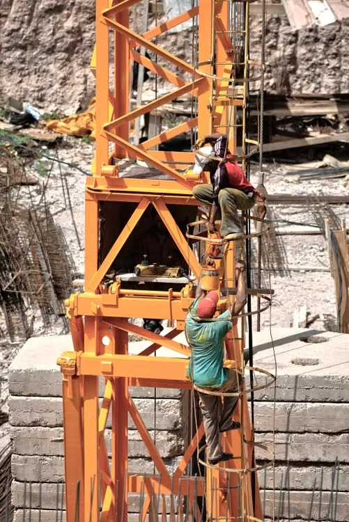 Des ouvriers interviennent sur la structure orange d’une grue.